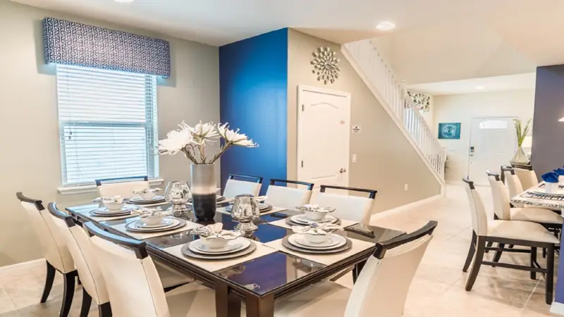 Dining – A dining area with a glass table set for six, white chairs, and a vase with flowers.