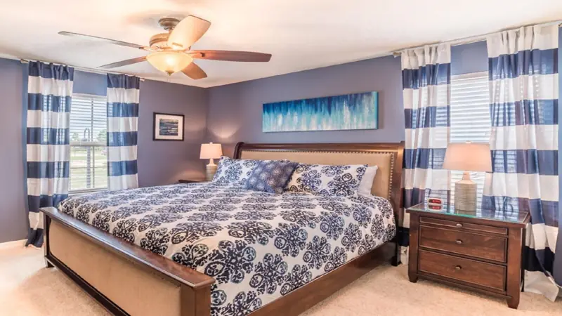 upstairs master king, a total of 4 kings – A bedroom with a bed, nightstands, a ceiling fan, and a painting on the wall.