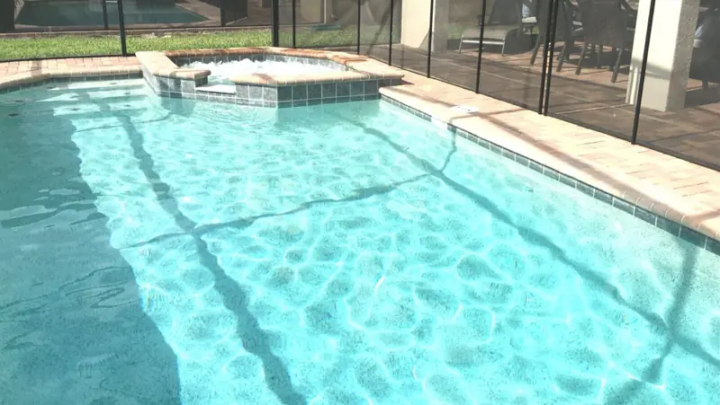Private hot tub and pool – A swimming pool with clear water, a hot tub, and a patio area with chairs and a table.